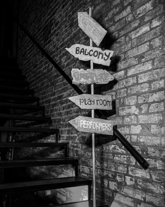 Hand-painted signposts pointing to the balcony, wax play, playroom and performers.